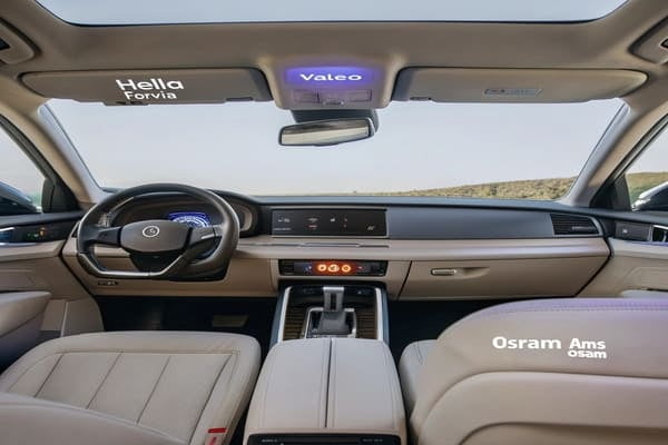 The interior of a luxury car at night, with multi-color ambient lighting along the dashboard and doors.
