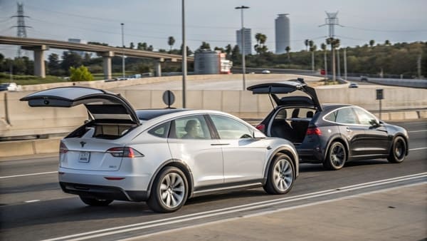 A Tesla Model X with its falcon-wing doors open in a crowded parking lot