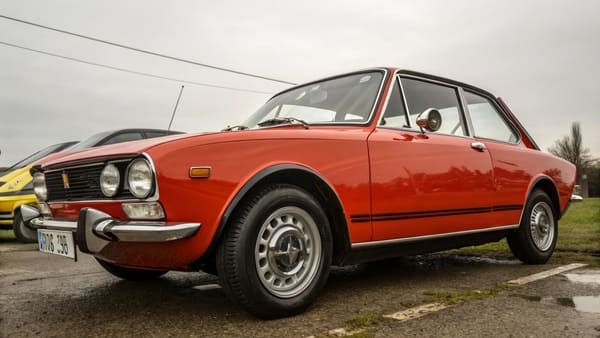 A classic 1970s muscle car parked at a show, gleaming under the sun