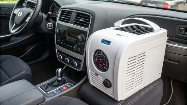 A person relaxing in an RV with a portable air conditioner running.