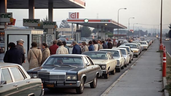 A long line of cars waiting at a gas station in the 1970s