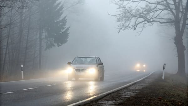 A car's front fog lamp illuminated in a foggy setting