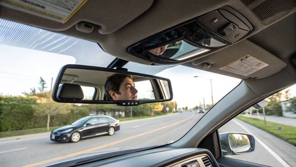 A hand flipping down a car's sun visor.