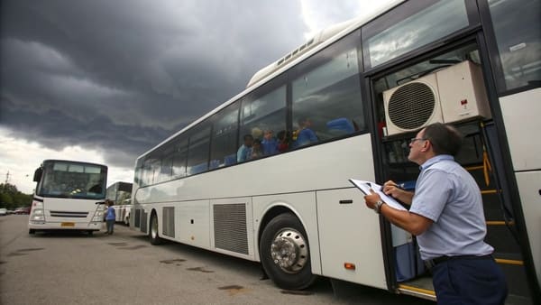 A modern bus with a rooftop air conditioning unit visible.