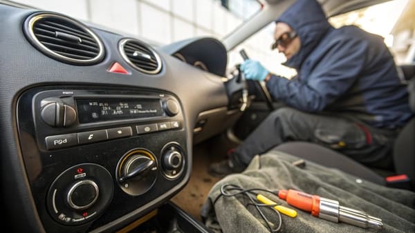 A mechanic visually inspecting an AC compressor in an engine with a flashlight.