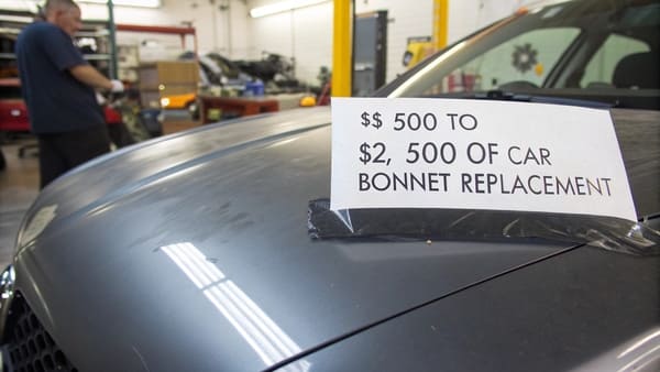 An aftermarket car bonnet being test-fitted on a vehicle