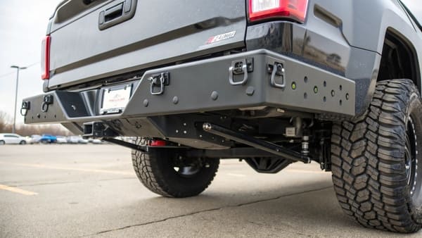 A truck with a steel bumper towing a small trailer
