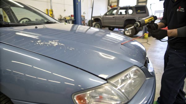 A car hood being prepped for painting in a body shop.